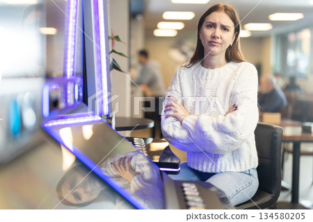 Sad young woman playing slot machine in cafe Sad young woman playing slot machine in cafe 134580205