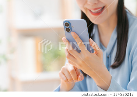 一個操作智能手機的年輕女子 一個操作智能手機的年輕女子 134580212