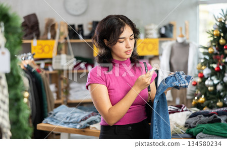 Asian woman chooses jeans against the background of the Christmas tree 134580234
