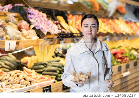 Female shopper selects ginger root in supermarket 134580237