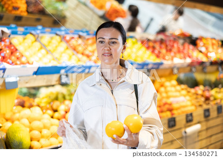 Middle-aged woman holding lemons in grocery store 134580271