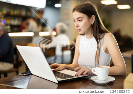 Young woman working on laptop in cafe Young woman working on laptop in cafe 134580275