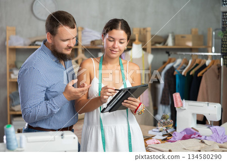 Female fashion designer creating custom clothing design with client in sewing studio 134580290