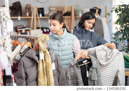 Teenage girl with her mother chooses coat or down jacket 134580292