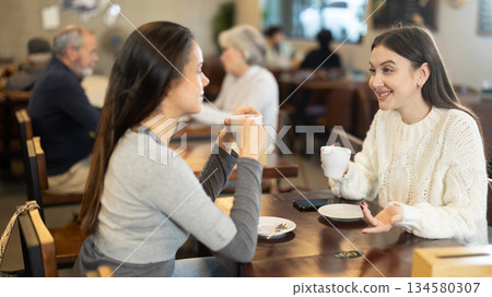 Two young women drinking coffee and talking in cafe 134580307