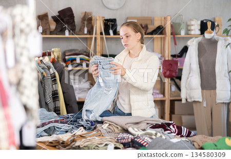 Selective teen girl choosing jean pantaloons in clothing store 134580309