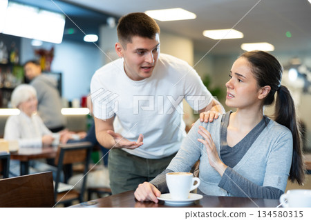 woman is sitting at a table in a coffee shop and does not want to meet a guy woman is sitting at a table in a coffee shop and does not want to meet a guy 134580315