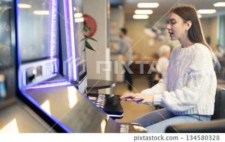 Young woman sitting near slot machine in video game Young woman sitting near slot machine in video game 134580328
