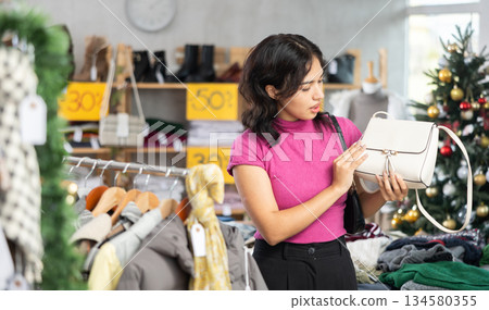 Filipino woman chooses a stylish handbag at Christmas sale 134580355