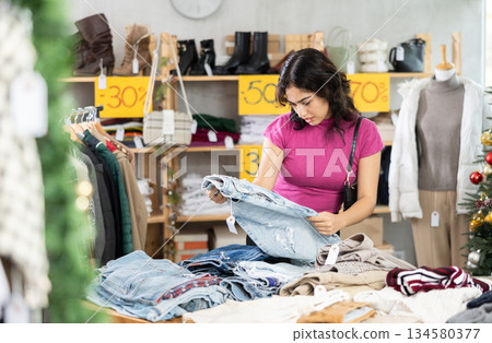 Asian woman chooses jeans against the background of the Christmas tree 134580377
