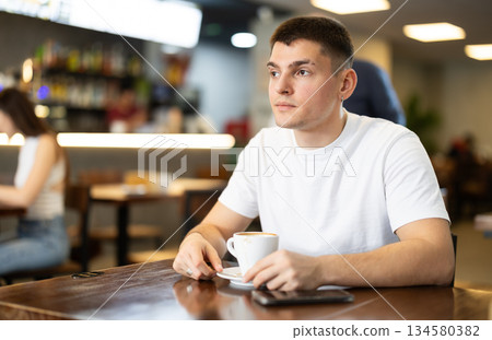Young man drinks coffee in cafe 134580382