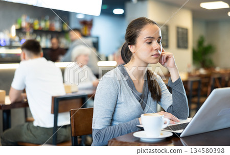 Young woman with laptop drinking coffee 134580398
