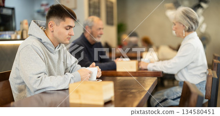 Guy whiles away time and drink coffee in cafe 134580451