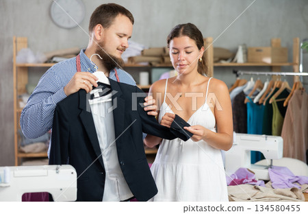 Male dressmaker showing finished jacket to young girl 134580455