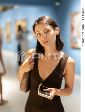 Young woman in summer clothes looking at paintings in museum 134580508