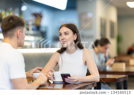 Girl in cafe sits near guy companion, has nice conversation Girl in cafe sits near guy companion, has nice conversation 134580515
