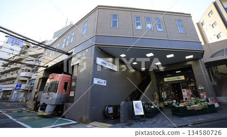 京王井之頭線新泉站北出口,設有自動扶梯,一列列車即將駛離車站。 京王井之頭線新泉站北出口,設有自動扶梯,一列列車即將駛離車站。 134580726