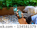 Electrician uses tools to fix circuit board while sitting in construction area 134581379