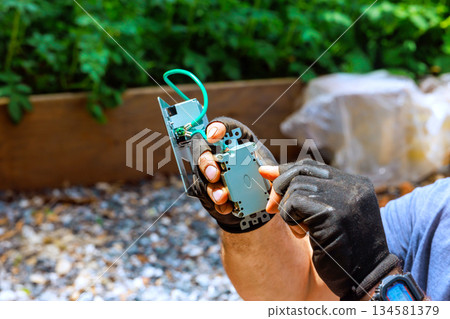 Electrician uses tools to fix circuit board while sitting in construction area Electrician uses tools to fix circuit board while sitting in construction area 134581379