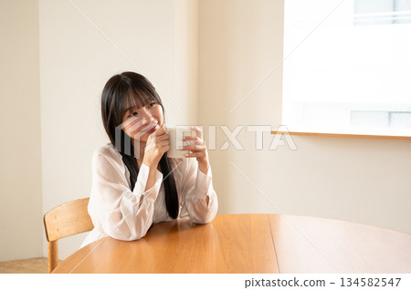 年輕女子在房間裡喝熱飲 年輕女子在房間裡喝熱飲 134582547