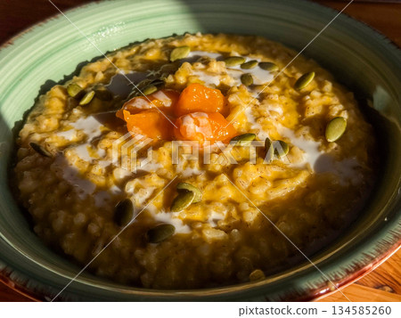 Creamy pumpkin seed oatmeal bowl with milk orange carrot chunks and seeds Creamy pumpkin seed oatmeal bowl with milk orange carrot chunks and seeds 134585260