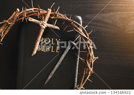Crown of thorns, wooden cross, iron nail placed on Holy Bible, symbolizing Christian faith, sacrifice, crucifixion, Easter reflection, religion background for worship, spiritual concept 134586922