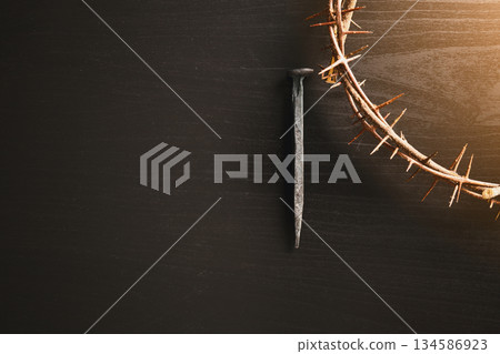 Crown of thorns, wooden cross, iron nail placed on Holy Bible, symbolizing Christian faith, sacrifice, crucifixion, Easter reflection, religion background for worship, spiritual concept 134586923