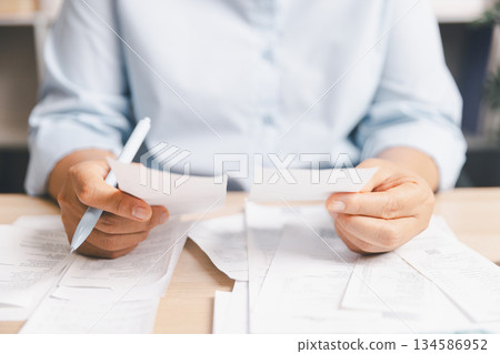 Business person reviewing multiple receipts, expense documents at desk, illustrating financial management, bill checking, budgeting, accounting workflow, cost tracking, daily office financial tasks. 134586952