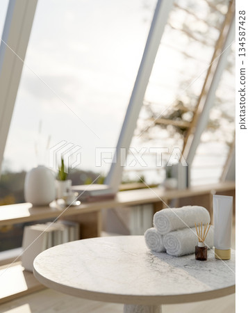 Towels with diffuser and lotion on grey marble table and bookshelf under sloped windows sunlit room. Towels with diffuser and lotion on grey marble table and bookshelf under sloped windows sunlit room. 134587428