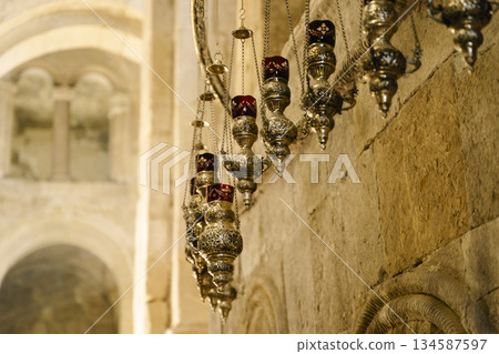 Intricate Antique Orthodox Oil Lamps Hanging in Stone Church Intricate Antique Orthodox Oil Lamps Hanging in Stone Church 134587597
