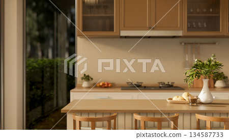 Breads on plate and a glass of coffee next to a flower vase on wooden counter with chairs in kitchen 134587733