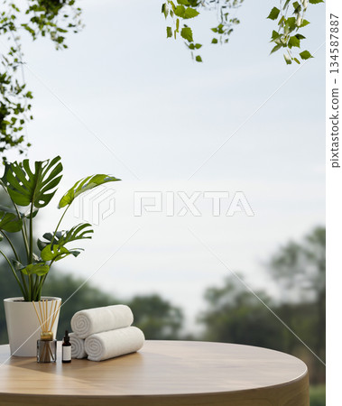 White towels and aroma diffuser aside potted plant on round wooden table with forest scenery and sky 134587887