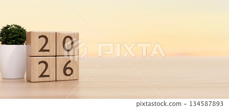 2026 new year countdown wooden blocks calendar aside potted plant on counter table in warm light. 2026 new year countdown wooden blocks calendar aside potted plant on counter table in warm light. 134587893
