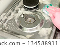 Hand in rubber glove cleaning stainless steel gas stove with sponge and soap foam. Cleaning concept. 134588911