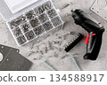 Electric screwdriver with set of metal screws drill bits on workshop table. DIY repair tools concept 134588917