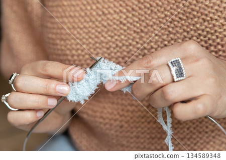 Hands Knitting Soft White Yarn Close-Up. A woman knit with knitting needles,closeup shot 134589348