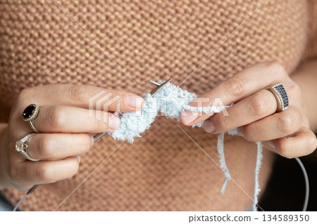 Knitting White Wool Thread in Cozy Setting. A woman knit with knitting needles,closeup shot 134589350