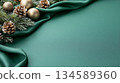 Elegant Christmas background with green fabric, pinecones, and golden ornaments for festive design 134589360