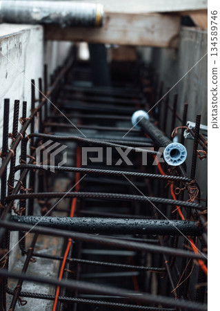 Construction site featuring steel reinforcement bars and pipes arranged in a framework, showcasing the intricate details of structural engineering and construction processes Construction site featuring steel reinforcement bars and pipes arranged in a framework, showcasing the intricate details of structural engineering and construction processes 134589746