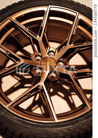 Winter tyres. Stylish bronze alloy wheel with intricate design and deep grooves, showcasing modern automotive aesthetics and craftsmanship, ideal for enhancing vehicle appearance 134589779