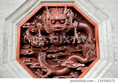 Intricate wooden dragon carving in octagonal frame Intricate wooden dragon carving in octagonal frame 134590372
