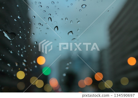City lights at dusk seen through a windshield with water droplets (cool colors, blurred background) 134590697
