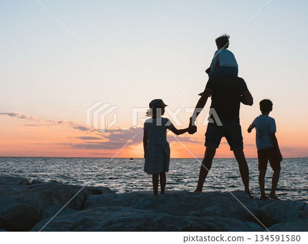 Father with Children Watching Sunset by the Sea Father with Children Watching Sunset by the Sea 134591580