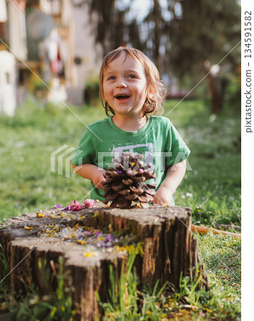 Joyful Child Playing with Pinecone Outdoors 134591582