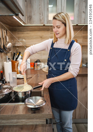 Cooking creamy pasta in a modern kitchen filled with warm light and joy Cooking creamy pasta in a modern kitchen filled with warm light and joy 134591646