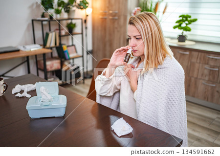 Woman in cozy home environment using inhaler during cold winter day Woman in cozy home environment using inhaler during cold winter day 134591662