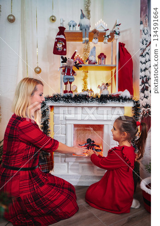 Mother daughter enjoying Christmas holiday with festive fireplace Mother daughter enjoying Christmas holiday with festive fireplace 134591664