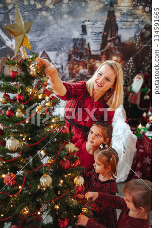 Family enjoying decorating Christmas tree together in festive setting Family enjoying decorating Christmas tree together in festive setting 134591665