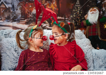 Little girls wearing reindeer costumes celebrating Christmas holiday Little girls wearing reindeer costumes celebrating Christmas holiday 134591667