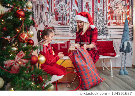 Mother giving daughter Christmas gift from Santa sack Mother giving daughter Christmas gift from Santa sack 134591687